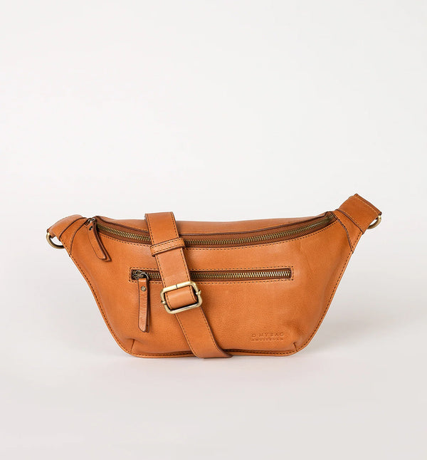 Drew Bum Bag från O My Bag. Lika praktisk som snygg! Den här designen är gjord av O My Bags mjuka narvläder och är perfekt för dem som vill ha med sig mer än bara en telefon och plånbok. Drew passar en 0,5 liters vattenflaska samt andra nödvändigheter. Med en ficka med dragkedja på fram- och baksidan, invändiga glidfickor och en säker dragkedja; denna väska kommer också med två justerbara remmar. Ett läderband och ett rutigt band. Färg cognac