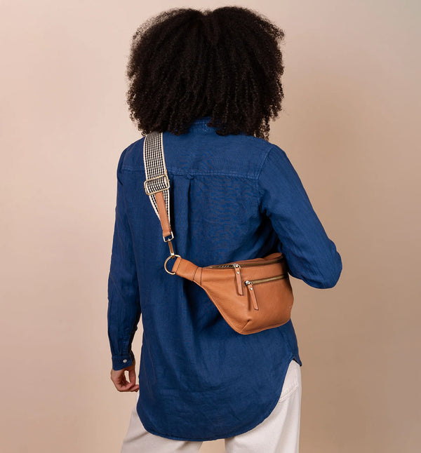 Drew Bum Bag från O My Bag. Lika praktisk som snygg! Den här designen är gjord av O My Bags mjuka narvläder och är perfekt för dem som vill ha med sig mer än bara en telefon och plånbok. Drew passar en 0,5 liters vattenflaska samt andra nödvändigheter. Med en ficka med dragkedja på fram- och baksidan, invändiga glidfickor och en säker dragkedja; denna väska kommer också med två justerbara remmar. Ett läderband och ett rutigt band. Färg cognac