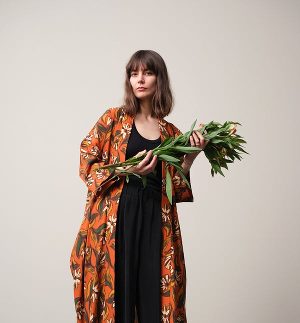 Lieblings kimono Gro i tyget Thalia. En lång lyxig kimono med fina kragdetaljer. Band att knyta i midjan. I kollektion Ridå har vi gjort Gro lite kortare än tidigare och i två storlekar. Tidigare onesize är nu S/M. 
Färg: Blommor i grönt, gult, brunt och vitt på orange botten.
Material: 51% EcoVero, 49% viskos från Frankrike.