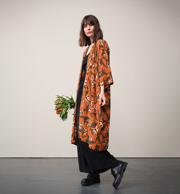 Lieblings kimono Gro i tyget Thalia. En lång lyxig kimono med fina kragdetaljer. Band att knyta i midjan. I kollektion Ridå har vi gjort Gro lite kortare än tidigare och i två storlekar. Tidigare onesize är nu S/M. 
Färg: Blommor i grönt, gult, brunt och vitt på orange botten.
Material: 51% EcoVero, 49% viskos från Frankrike.