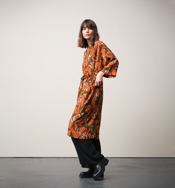 Lieblings kimono Gro i tyget Thalia. En lång lyxig kimono med fina kragdetaljer. Band att knyta i midjan. I kollektion Ridå har vi gjort Gro lite kortare än tidigare och i två storlekar. Tidigare onesize är nu S/M. 
Färg: Blommor i grönt, gult, brunt och vitt på orange botten.
Material: 51% EcoVero, 49% viskos från Frankrike.