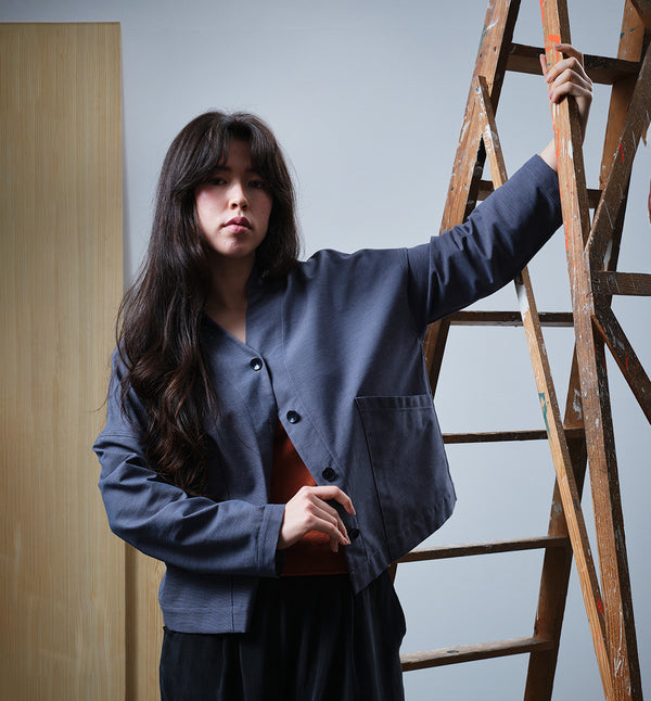 Jackie kimonojacka är lite boxig i modellen, v-ringad, två stora fickor fram, ok i ryggen och fyra knappar fram.  
Färg: Mörkblå med smala vita ränder. Mörkblå knappar.
Material: 99% bomull, 1% lin.
