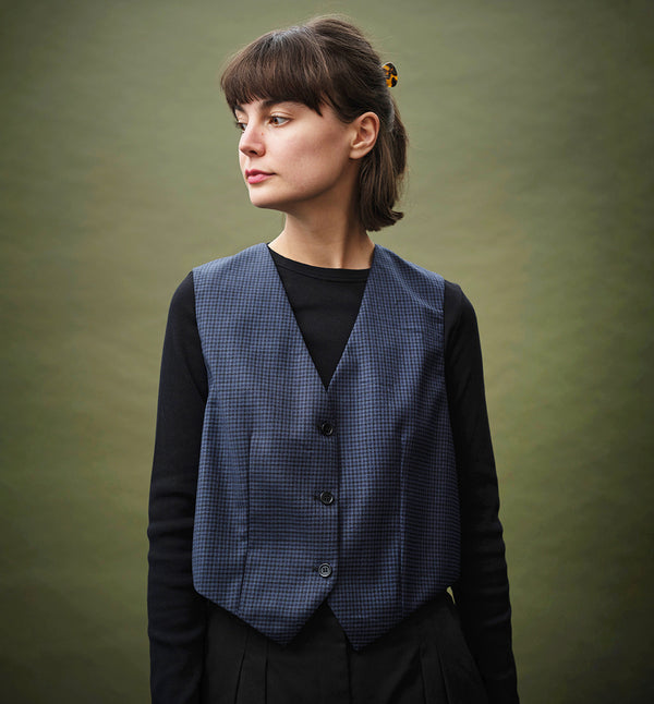 Liv är vår klassiska herrväst i damtappning. Liv Älv är sydd i ett smårutigt ull och polyestertyg. Svart foder och bakstycke.
Färg: Smårutig blå/svart. Svart foder.
Material: 55% polyester, 45% ull. Foder 100% viskos.
Materialursprung: Detta är resttyger från det svenska företaget Rekotex som jobbar med deadstocktyger, dvs överproduktion från textilindustrin runt om i Europa.  