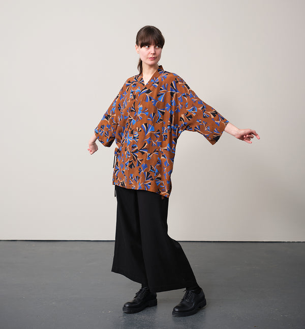 Jinbei kimono Miko! Med inspiration från japanska formspråket har vi designat en kimono som är avslappnat stylish. Knyts omlott och har en ficka fram. 
Färg: Mönster i kornblått, svart och beige på nougatbrun botten.
Material: 51% EcoVero, 49% viskos från Frankrike.