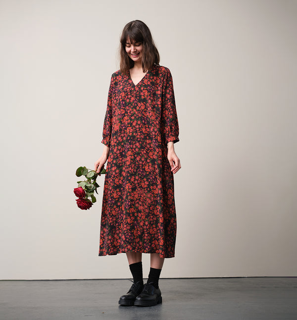 Vår klänning Nea! V-ringad, söm i midjan, trekvarts ärm med smal manschett och knapp, fickor i sidorna.  
Färg: Blommor i roströda, mörklila, gröna och orangea toner på svart botten.
Material: 51% EcoVero, 49% viskos från Frankrike.