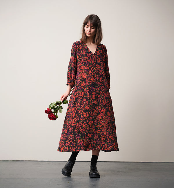 Vår klänning Nea! V-ringad, söm i midjan, trekvarts ärm med smal manschett och knapp, fickor i sidorna.  
Färg: Blommor i roströda, mörklila, gröna och orangea toner på svart botten.
Material: 51% EcoVero, 49% viskos från Frankrike.