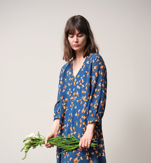 Vår klänning Nea Paradiso! V-ringad, söm i midjan, trekvarts ärm med smal manschett och fickor i sidorna.  
Färg: Blommor i gula, beiga och gröna toner på blå botten.
Material: 51% EcoVero, 49% viskos från Frankrike.