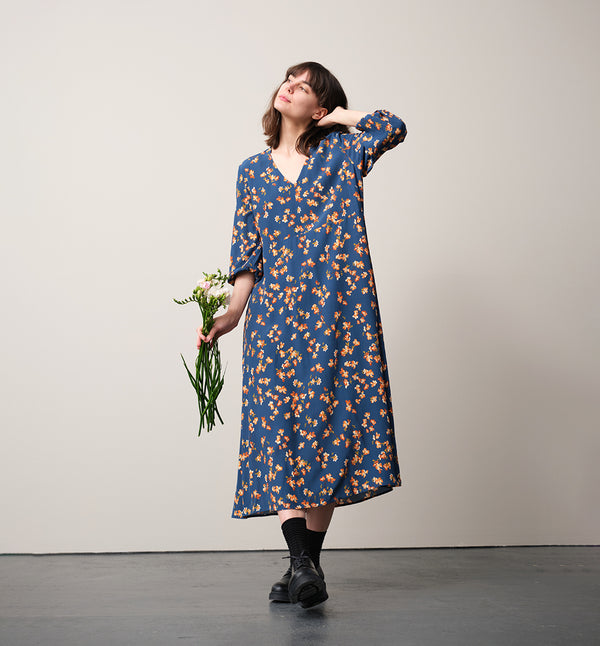 Vår klänning Nea Paradiso! V-ringad, söm i midjan, trekvarts ärm med smal manschett och fickor i sidorna.  
Färg: Blommor i gula, beiga och gröna toner på blå botten.
Material: 51% EcoVero, 49% viskos från Frankrike.