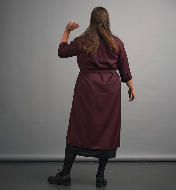 Lieblings klänning Svala Björnbär. En ankellång skjortklänning med lös passform, trekvartsärm och fickor i sidorna. Ok med rynk i ryggen. Ett 2,5 cm brett band i samma tyg medföljer och kan knytas i midjan. Svala är fin både öppen och stängd, med eller utan band. Mörkt vinröda knappar mitt fram och vid ärmslut. Sydd i ett deadstocktyg från Rekotex.