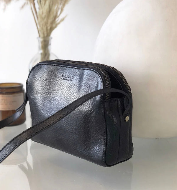 Svart Handväska Emily från märket O My Bag. Emily består av tre fack som gör den här väskan perfekt för dem som gillar att hålla ordning. Den har två stängda fack med blixtlås för alla dina värdesaker, och ett fack med magnetisk stängning. Justerbar axelrem i läder.