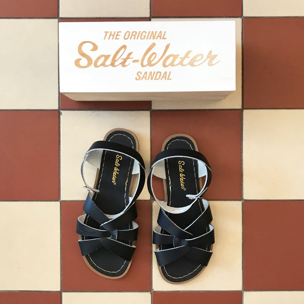 Svarta sandaler från det amerikanska märket Salt-Water Sandal. Modellen heter Original. Original har flätat läder över foten och knäpps med spänne över vristen. Svarta