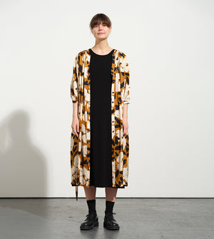 Liebling klänning Bonnie! Bonnie är en smula countryinspirerad i modellen. V-ringad, puffiga ärmar, fickor i sidorna och band att knyta i midjan. Rundat ok bak. Armbågslång ärm med smal manschett med en knapp. Svarta knappar mitt fram. Tyget är blankt vilket ger en lyxig känsla!&nbsp;

Färg: Vita blommor och svarta blad på guldbrun botten.&nbsp;

Material: 51% EcoVero, 49% viskos från Frankrike.