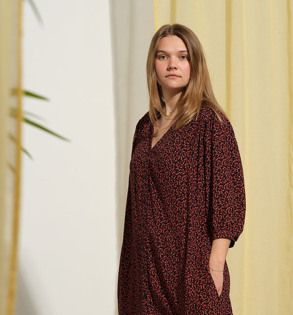 Liebling klänning Bonnie! Bonnie är en smula countryinspirerad i modellen. V-ringad, puffiga ärmar, fickor i sidorna och band att knyta i midjan. Rundat ok bak. Armbågslång ärm med smal manschett med en knapp. Svarta knappar mitt fram.

Färg: Små röda blommor på svart botten

Material: 51% EcoVero, 49% viskos från Frankrike.