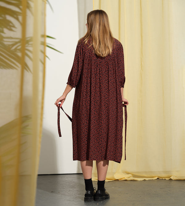 Liebling klänning Bonnie! Bonnie är en smula countryinspirerad i modellen. V-ringad, puffiga ärmar, fickor i sidorna och band att knyta i midjan. Rundat ok bak. Armbågslång ärm med smal manschett med en knapp. Svarta knappar mitt fram.

Färg: Små röda blommor på svart botten

Material: 51% EcoVero, 49% viskos från Frankrike.