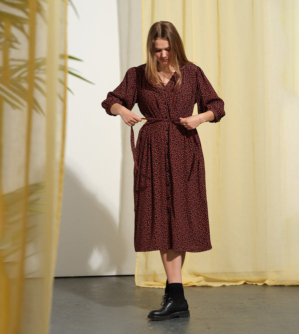 Liebling klänning Bonnie! Bonnie är en smula countryinspirerad i modellen. V-ringad, puffiga ärmar, fickor i sidorna och band att knyta i midjan. Rundat ok bak. Armbågslång ärm med smal manschett med en knapp. Svarta knappar mitt fram.

Färg: Små röda blommor på svart botten

Material: 51% EcoVero, 49% viskos från Frankrike.