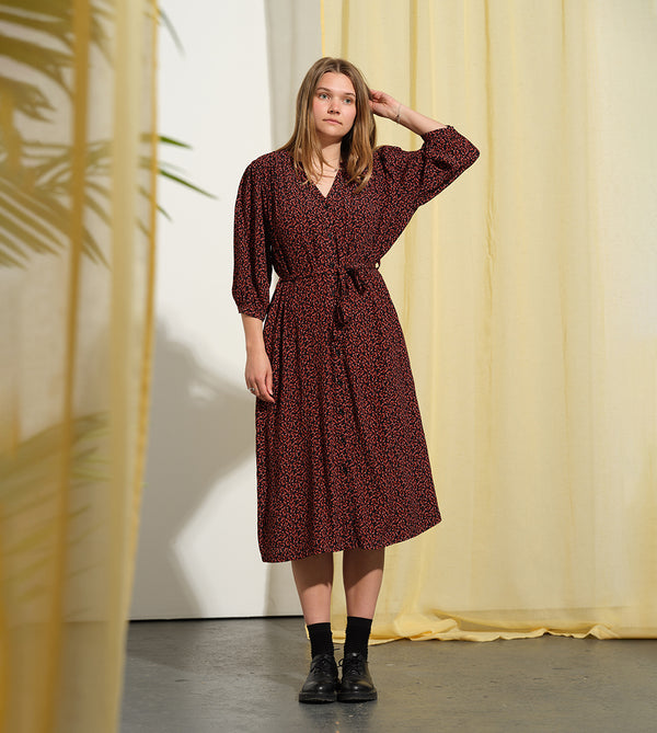 Liebling klänning Bonnie! Bonnie är en smula countryinspirerad i modellen. V-ringad, puffiga ärmar, fickor i sidorna och band att knyta i midjan. Rundat ok bak. Armbågslång ärm med smal manschett med en knapp. Svarta knappar mitt fram.

Färg: Små röda blommor på svart botten

Material: 51% EcoVero, 49% viskos från Frankrike.