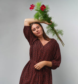 Liebling klänning Bonnie! Bonnie är en smula countryinspirerad i modellen. V-ringad, puffiga ärmar, fickor i sidorna och band att knyta i midjan. Rundat ok bak. Armbågslång ärm med smal manschett med en knapp. Svarta knappar mitt fram.

Färg: Små röda blommor på svart botten

Material: 51% EcoVero, 49% viskos från Frankrike.