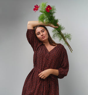Liebling klänning Bonnie! Bonnie är en smula countryinspirerad i modellen. V-ringad, puffiga ärmar, fickor i sidorna och band att knyta i midjan. Rundat ok bak. Armbågslång ärm med smal manschett med en knapp. Svarta knappar mitt fram.

Färg: Små röda blommor på svart botten

Material: 51% EcoVero, 49% viskos från Frankrike.