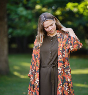 Lieblings kimono Gro i tyget Thalia. En lång lyxig kimono med fina kragdetaljer. Band att knyta i midjan.&nbsp;I kollektion Ridå har vi gjort Gro lite kortare än tidigare och i två storlekar. Tidigare onesize är nu S/M.&nbsp;

Färg: Blommor i grönt, gult, brunt och vitt på orange botten.

Material: 51% EcoVero, 49% viskos från Frankrike.