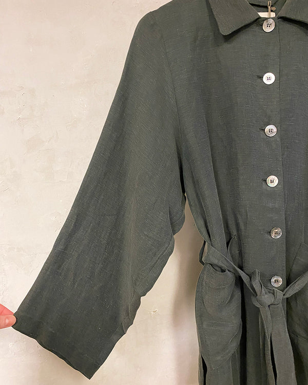 Skjortjacka Holmön från Bric-a-brac i en härlig cupro- och linneblandning. Två fickor fram, vida ärmar och bälte att knyta i midjan. Ok med veck bak. Pärlemorknappar.  Färg: Grågrön Material: 58% linne, 42% cupro.