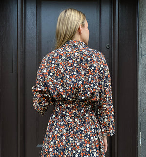 Klänningen Humla är en riktigt Lieblingfavorit. En ankellång kappklänning som kan bäras både öppen och stängd, som klänning eller kappa.&nbsp;Humla är en smula japaninspirerad i modellen och går att bära med eller utan det medföljande obi-bältet. Rak modell med krage, sprund bak och två fickor fram.&nbsp;

Färger: Små blommor i beige, vitt och orange på svart botten.

Material: 51% EcoVero, 49% viskos från Frankrike. 