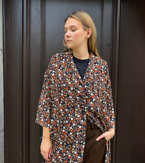 Klänningen Humla är en riktigt Lieblingfavorit. En ankellång kappklänning som kan bäras både öppen och stängd, som klänning eller kappa.&nbsp;Humla är en smula japaninspirerad i modellen och går att bära med eller utan det medföljande obi-bältet. Rak modell med krage, sprund bak och två fickor fram.&nbsp;

Färger: Små blommor i beige, vitt och orange på svart botten.

Material: 51% EcoVero, 49% viskos från Frankrike. 