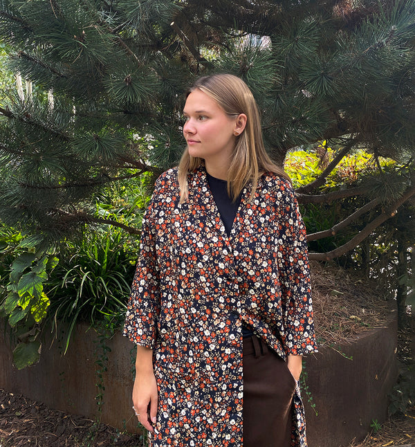 Klänningen Humla är en riktigt Lieblingfavorit. En ankellång kappklänning som kan bäras både öppen och stängd, som klänning eller kappa.&nbsp;Humla är en smula japaninspirerad i modellen och går att bära med eller utan det medföljande obi-bältet. Rak modell med krage, sprund bak och två fickor fram.&nbsp;

Färger: Små blommor i beige, vitt och orange på svart botten.

Material: 51% EcoVero, 49% viskos från Frankrike. 
