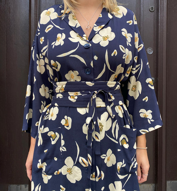 Klänningen Humla är en riktigt Lieblingfavorit. En ankellång kappklänning som kan bäras både öppen och stängd, som klänning eller kappa.&nbsp;Humla är en smula japaninspirerad i modellen och går att bära med eller utan det medföljande obi-bältet. Rak modell med krage, sprund bak och två fickor fram.&nbsp;

Färger: Gräddvita blommor med gula och olivgröna detaljer på mörkblå botten.

Material: 51% EcoVero, 49% viskos från Frankrike.