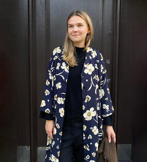 Klänningen Humla är en riktigt Lieblingfavorit. En ankellång kappklänning som kan bäras både öppen och stängd, som klänning eller kappa.&nbsp;Humla är en smula japaninspirerad i modellen och går att bära med eller utan det medföljande obi-bältet. Rak modell med krage, sprund bak och två fickor fram.&nbsp;

Färger: Gräddvita blommor med gula och olivgröna detaljer på mörkblå botten.

Material: 51% EcoVero, 49% viskos från Frankrike.