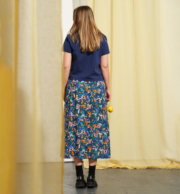 Kjolen Jojo! Avslappnad modell med veck fram, fickor i sidorna och resår med hällor i midjan. Sydd i en lyxig viskos med lite prickig struktur.&nbsp;

Färg: Blommor i orange, ljuslila, beige och klarblå på åskblå botten

Material: 51% EcoVero, 49% viskos från Frankrike.