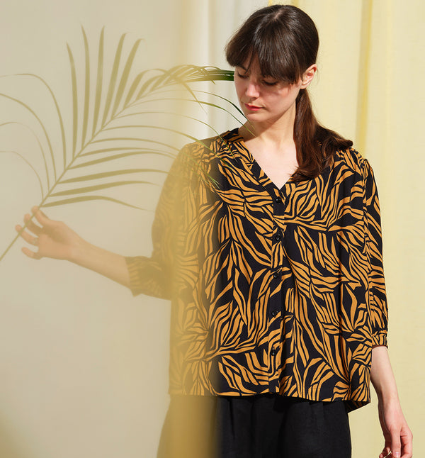  blus Lynn är en smula countryinspirerad i modellen. V-ringad, puffiga ärmar och rundat ok bak. Armbågslång ärm med smal manschett med en knapp. Svarta knappar mitt fram.

Färg: Ockragula palmblad på svart botten

Material: 51% EcoVero, 49% viskos från Frankrike