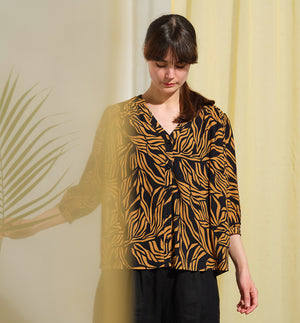  blus Lynn är en smula countryinspirerad i modellen. V-ringad, puffiga ärmar och rundat ok bak. Armbågslång ärm med smal manschett med en knapp. Svarta knappar mitt fram.

Färg: Ockragula palmblad på svart botten

Material: 51% EcoVero, 49% viskos från Frankrike