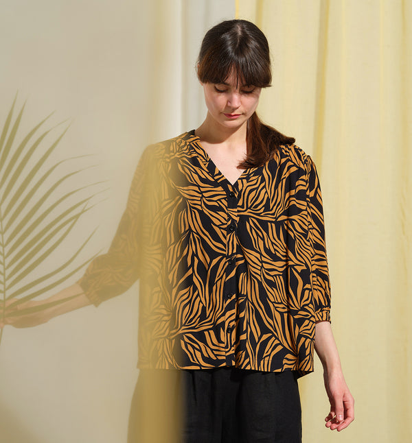  blus Lynn är en smula countryinspirerad i modellen. V-ringad, puffiga ärmar och rundat ok bak. Armbågslång ärm med smal manschett med en knapp. Svarta knappar mitt fram.

Färg: Ockragula palmblad på svart botten

Material: 51% EcoVero, 49% viskos från Frankrike