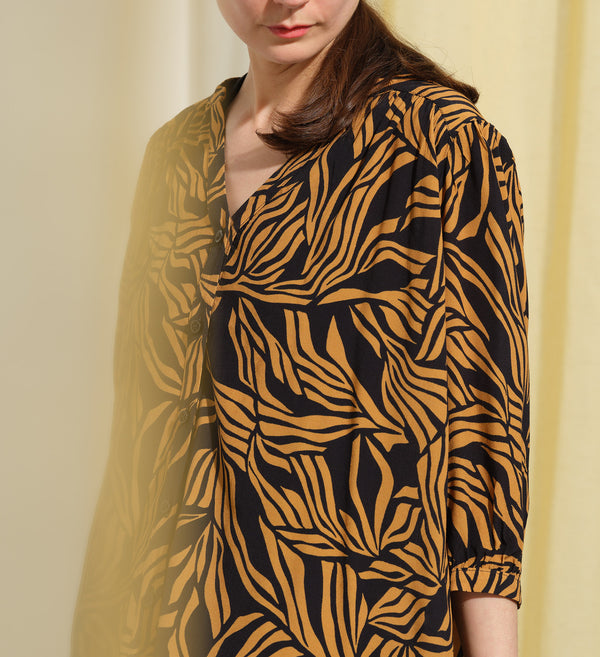  blus Lynn är en smula countryinspirerad i modellen. V-ringad, puffiga ärmar och rundat ok bak. Armbågslång ärm med smal manschett med en knapp. Svarta knappar mitt fram.

Färg: Ockragula palmblad på svart botten

Material: 51% EcoVero, 49% viskos från Frankrike