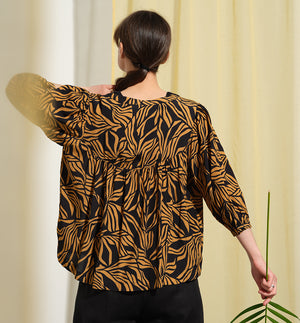  blus Lynn är en smula countryinspirerad i modellen. V-ringad, puffiga ärmar och rundat ok bak. Armbågslång ärm med smal manschett med en knapp. Svarta knappar mitt fram.

Färg: Ockragula palmblad på svart botten

Material: 51% EcoVero, 49% viskos från Frankrike