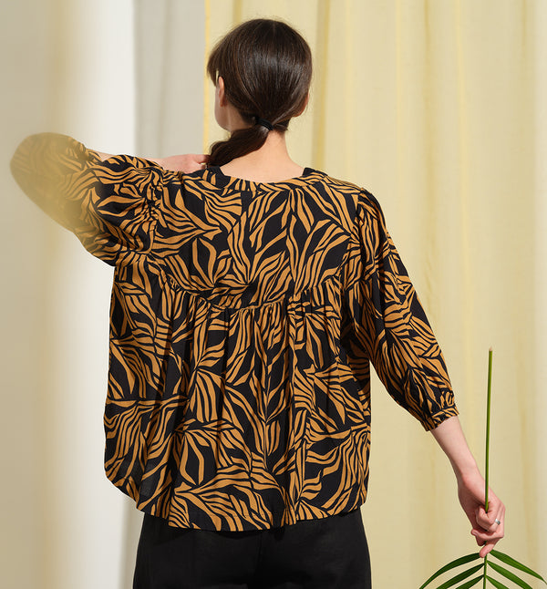  blus Lynn är en smula countryinspirerad i modellen. V-ringad, puffiga ärmar och rundat ok bak. Armbågslång ärm med smal manschett med en knapp. Svarta knappar mitt fram.

Färg: Ockragula palmblad på svart botten

Material: 51% EcoVero, 49% viskos från Frankrike