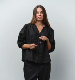 Liebling blus Lynn är en smula countryinspirerad i modellen. V-ringad, puffiga ärmar och rundat ok bak. Armbågslång ärm med smal manschett med en knapp. Svarta knappar mitt fram.

Färg: Svart

Material: 100% lin

Materialursprung: Detta tyg är ett deadstock tyg och kommer från Italien.