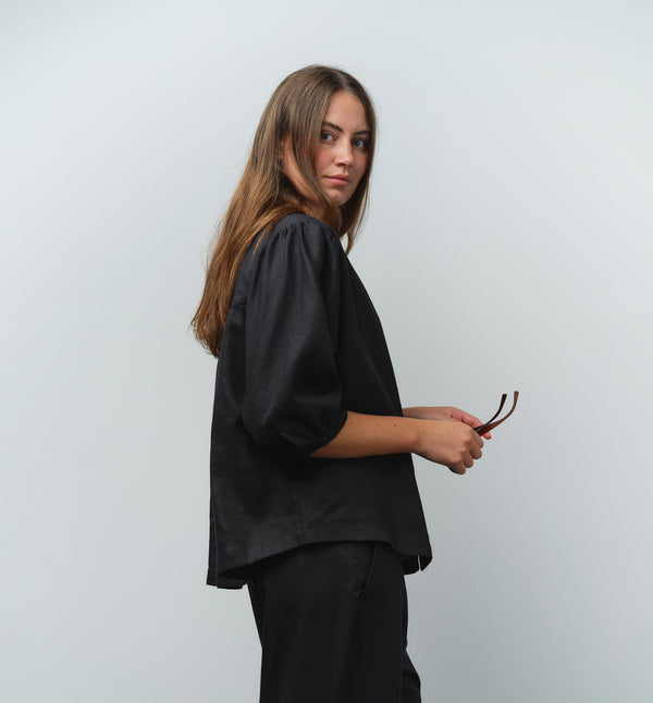 Liebling blus Lynn är en smula countryinspirerad i modellen. V-ringad, puffiga ärmar och rundat ok bak. Armbågslång ärm med smal manschett med en knapp. Svarta knappar mitt fram.

Färg: Svart

Material: 100% lin

Materialursprung: Detta tyg är ett deadstock tyg och kommer från Italien.