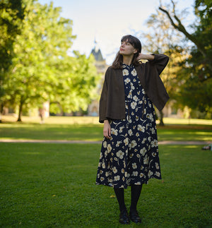  klänning Lyra. Murarkrage med avtagbart band. Knappslå fram med mörkblå knappar. Söm och rynk i midjan. Fickor i sidorna. Bandet knäpps på översta knappen. En fin detalj som ger Lyra fler stylingsmöjligheter. Sydd i en ekologisk viskos. Bandet ingår.

Färg: Gräddvita blommor med gula och olivgröna detaljer på mörkblå botten.

Material:&nbsp;51% EcoVero, 49% viskos från Frankrike. 