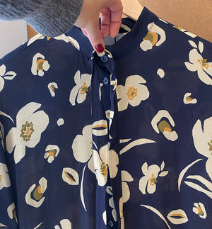  klänning Lyra. Murarkrage med avtagbart band. Knappslå fram med mörkblå knappar. Söm och rynk i midjan. Fickor i sidorna. Bandet knäpps på översta knappen. En fin detalj som ger Lyra fler stylingsmöjligheter. Sydd i en ekologisk viskos. Bandet ingår.

Färg: Gräddvita blommor med gula och olivgröna detaljer på mörkblå botten.

Material:&nbsp;51% EcoVero, 49% viskos från Frankrike. 