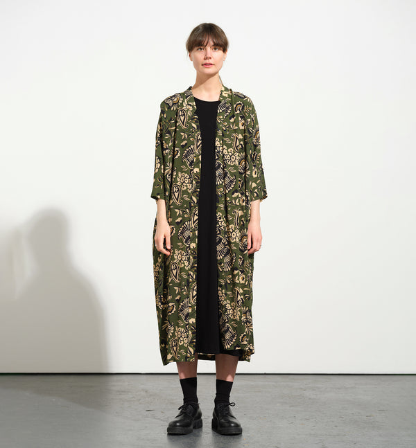 klänning Naja Lotus. En ankellång klänning med fina kragdetaljer. Ok med veck i ryggen, fickor i sidorna. Naja är fin både öppen och stängd. Små svarta knappar mitt fram. Sydd i en ekologisk viskos.

Färg: Blommor i beige, svart och gulgrönt på grön botten.

Material:&nbsp;51% EcoVero, 49% viskos från Frankrike.