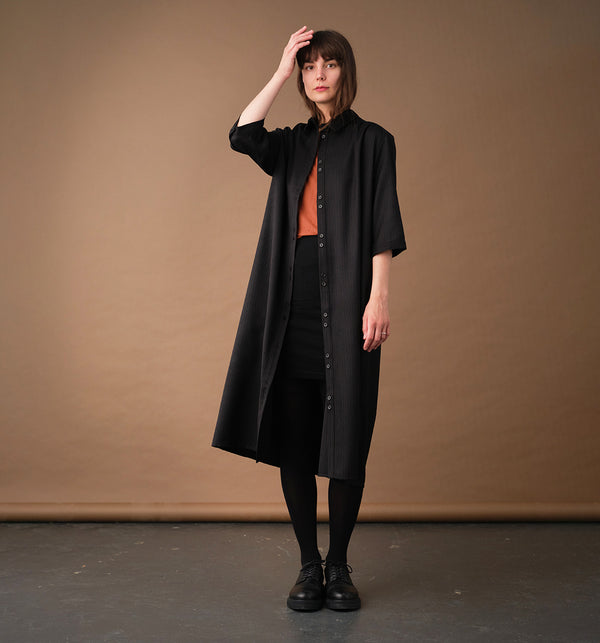 Lieblings klänning Svala Kritstreck. En ankellång skjortklänning med lös passform, trekvartsärm och fickor i sidorna. Ok med rynk i ryggen. Ett 2,5 cm brett band i samma tyg medföljer och kan knytas i midjan. Svala är fin både öppen och stängd, med eller utan band. Svarta knappar mitt fram och vid ärmslut. Sydd i ett deadstock tyg.

Färg: Svart med grå och roströda streck

Material: 100% ull
Designad i Malmö, Sverige, tillverkad i Litauen