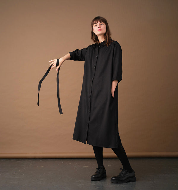 Lieblings klänning Svala Kritstreck. En ankellång skjortklänning med lös passform, trekvartsärm och fickor i sidorna. Ok med rynk i ryggen. Ett 2,5 cm brett band i samma tyg medföljer och kan knytas i midjan. Svala är fin både öppen och stängd, med eller utan band. Svarta knappar mitt fram och vid ärmslut. Sydd i ett deadstock tyg.

Färg: Svart med grå och roströda streck

Material: 100% ull
Designad i Malmö, Sverige, tillverkad i Litauen