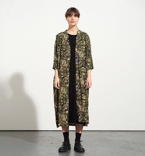 klänning Naja Lotus. En ankellång klänning med fina kragdetaljer. Ok med veck i ryggen, fickor i sidorna. Naja är fin både öppen och stängd. Små svarta knappar mitt fram. Sydd i en ekologisk viskos.

Färg: Blommor i beige, svart och gulgrönt på grön botten.

Material:&nbsp;51% EcoVero, 49% viskos från Frankrike.