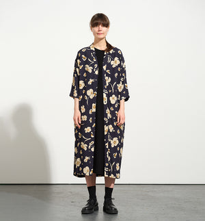 Vår klänning Naja Sonett. En ankellång klänning med fina kragdetaljer. Ok med veck i ryggen, fickor i sidorna. Naja är fin både öppen och stängd. Små mörkblå knappar mitt fram. Sydd i en ekologisk viskos.

Färg: Gräddvita blommor med gula och olivgröna detaljer på mörkblå botten.

Material:&nbsp;51% EcoVero, 49% viskos från Frankrike.
Designad i Malmö, tillverkad i Litauen