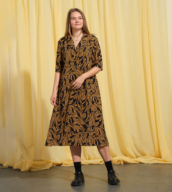 Lieblings  klänning Sally i tyget Cannes. Sally är en A-linjeformad klänning med krage, knappslå, ok med små veck i ryggen och fickor i sidorna. Band att knyta i midjan.&nbsp;

Färg: Ockragula palmblad på svart botten

Material: 51% EcoVero, 49% viskos från Frankrike. Tillverkad i:&nbsp;Litauen
Designad i:&nbsp;Malmö

Upplaga: 65 st