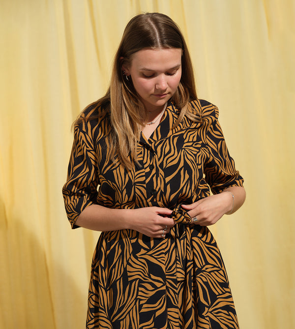 Lieblings  klänning Sally i tyget Cannes. Sally är en A-linjeformad klänning med krage, knappslå, ok med små veck i ryggen och fickor i sidorna. Band att knyta i midjan.&nbsp;

Färg: Ockragula palmblad på svart botten

Material: 51% EcoVero, 49% viskos från Frankrike. Tillverkad i:&nbsp;Litauen
Designad i:&nbsp;Malmö

Upplaga: 65 st