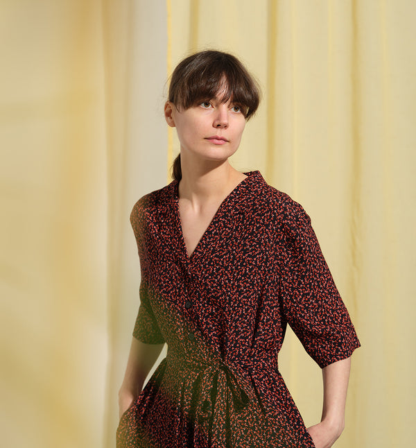 Liebling klänning Sally i tyget Rio. Sally är en A-linjeformad klänning med krage, knappslå, ok med små veck i ryggen och fickor i sidorna. Band att knyta i midjan.&nbsp;

Färg: Små röda blommor på svart botten

Material: 51% EcoVero, 49% viskos från Frankrike. 
Tillverkad i:&nbsp;Litauen
Designad i:&nbsp;Malmö