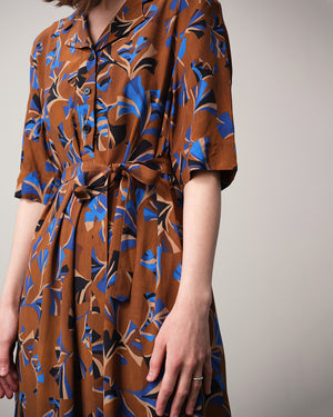 Vår klänning Sally i tyget Tosca.&nbsp;Sally är A-linjeformad med krage, knappslå, ok med små veck i ryggen och fickor i sidorna. Band att knyta i midjan.&nbsp;

Färg: Mönster i kornblått, svart och beige på nougatbrun botten.

Material: 51% EcoVero, 49% viskos från Frankrike.