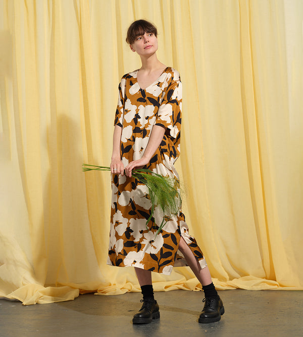 Liebling klänning Sparv i tyget Kokos.&nbsp;Lyxigt enkel kaftanklänning till årets alla fester. Rak modell, v-ringning, sidfickor och slits i sidorna. Obibälte ingår.&nbsp;Bältet är&nbsp;lätt vadderat och passar även fint att ha till annat:) Tyget är lite blankt vilket ger en extra lyxig känsla!&nbsp;

Färg: Vita blommor och svarta blad på guldbrun botten.

Material: 51% EcoVero, 49% viskos från Frankrike. 
Designad i Malmö, sydd i Litauen